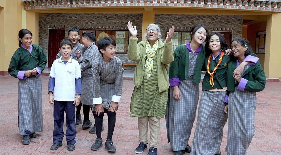 A teacher and her students laughing together in a school courtyard in Bhutan